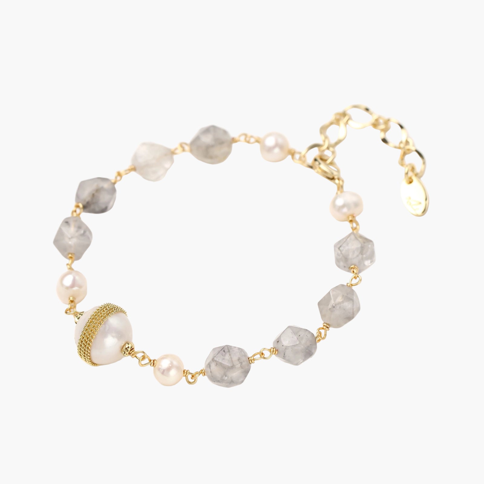 Bracelet with cloudy quartz beads, freshwater pearls, and gold-wrapped baroque pearl centerpiece on white background.