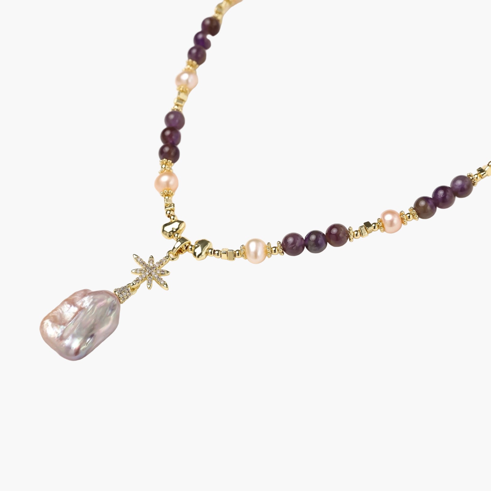 Gold necklace with iridescent baroque pearl pendant, purple amethyst beads, and crystal star charm on cream background