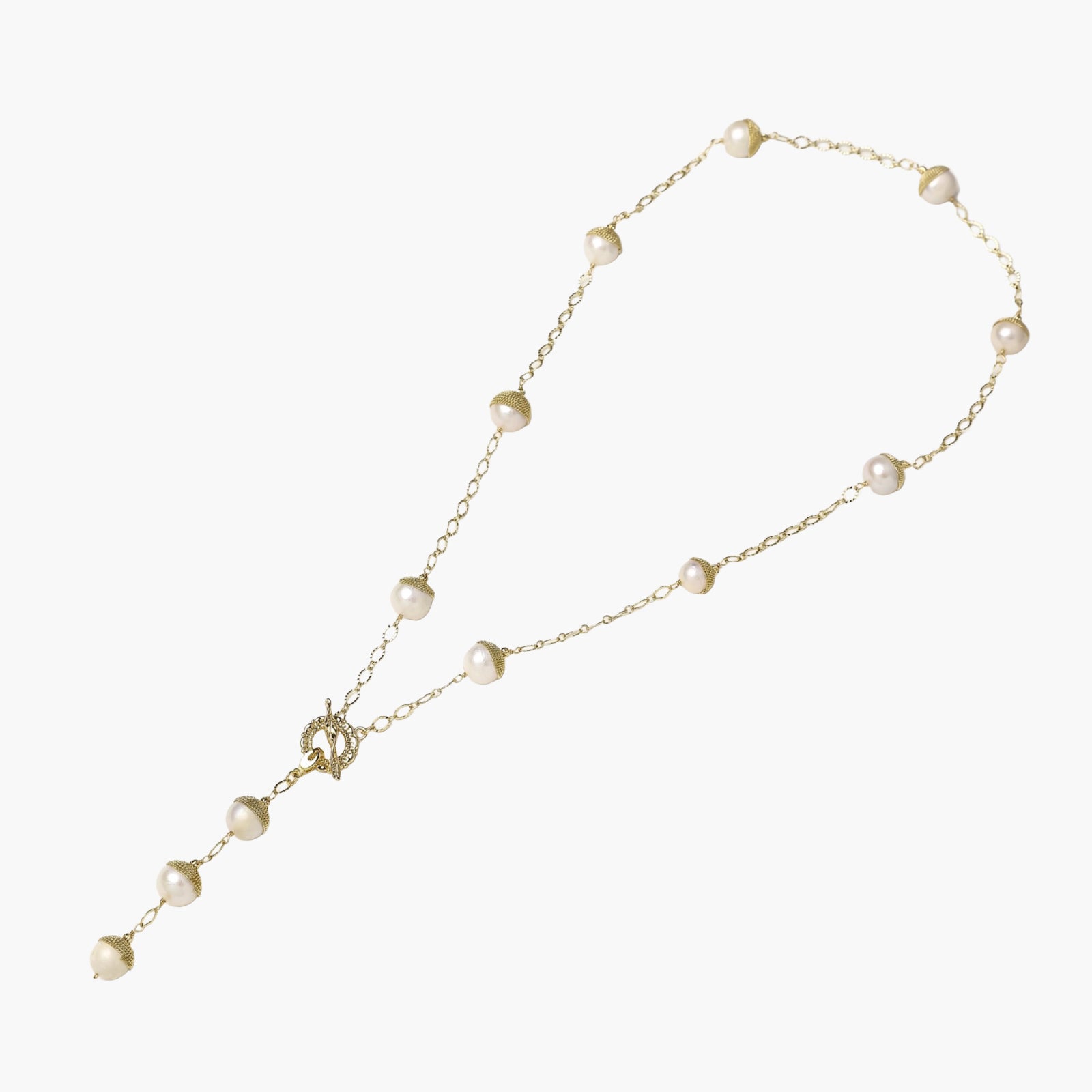 Gold-plated lariat necklace with baroque pearls and textured caps on cream background, showing adjustable Y-shaped design.