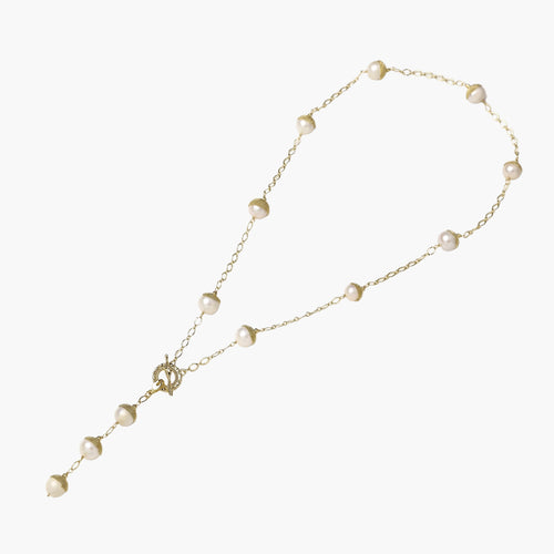 Gold-plated lariat necklace with baroque pearls and textured caps on cream background, showing adjustable Y-shaped design.
