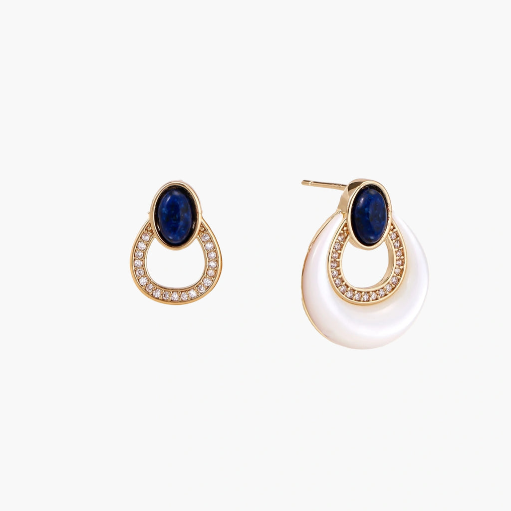 Gold drop earrings with oval lapis lazuli, crystal-paved frame, and iridescent mother-of-pearl teardrop on cream background