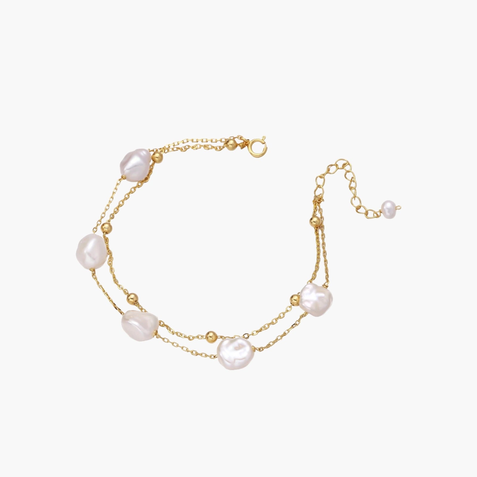 Double-strand gold bracelet with irregular baroque pearls and smooth freshwater pearls on cream background.