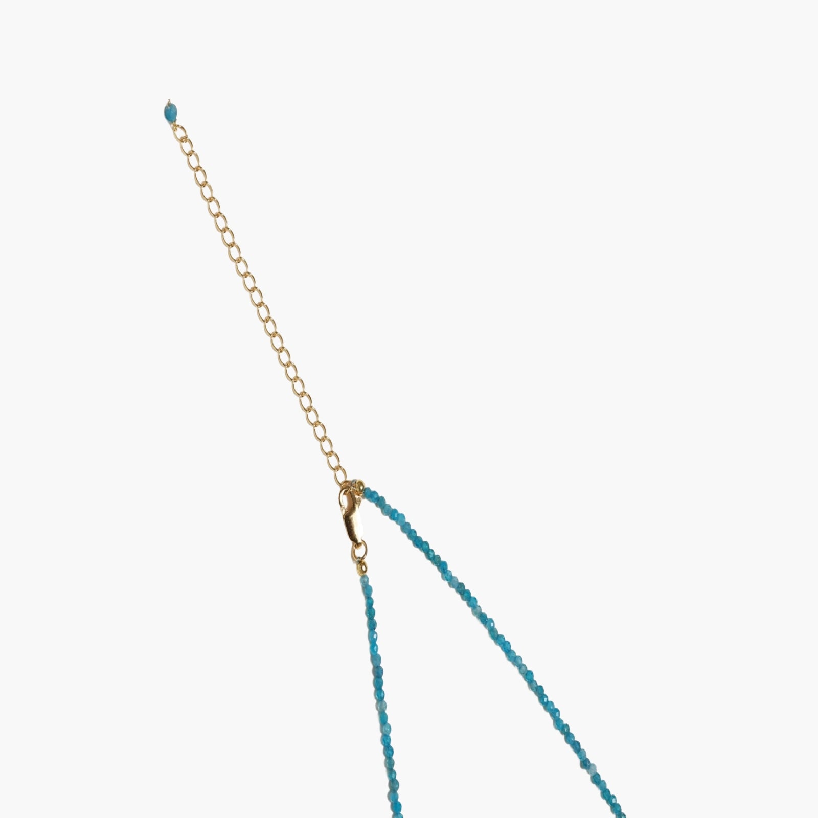 Delicate gold vermeil necklace with teal apatite beads and freshwater pearl on white background.