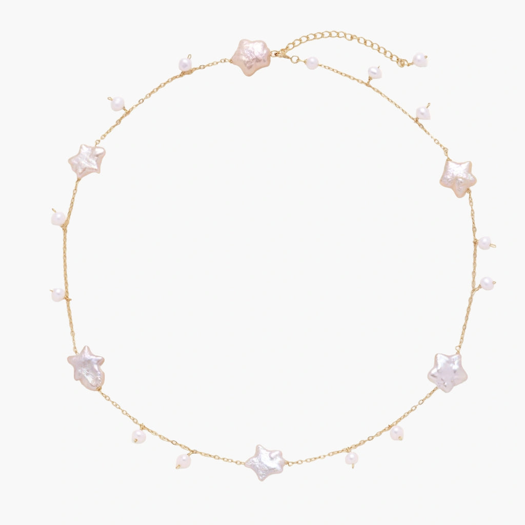 Gold vermeil chain with iridescent star-shaped baroque pearls and small round freshwater pearl drops on cream background.