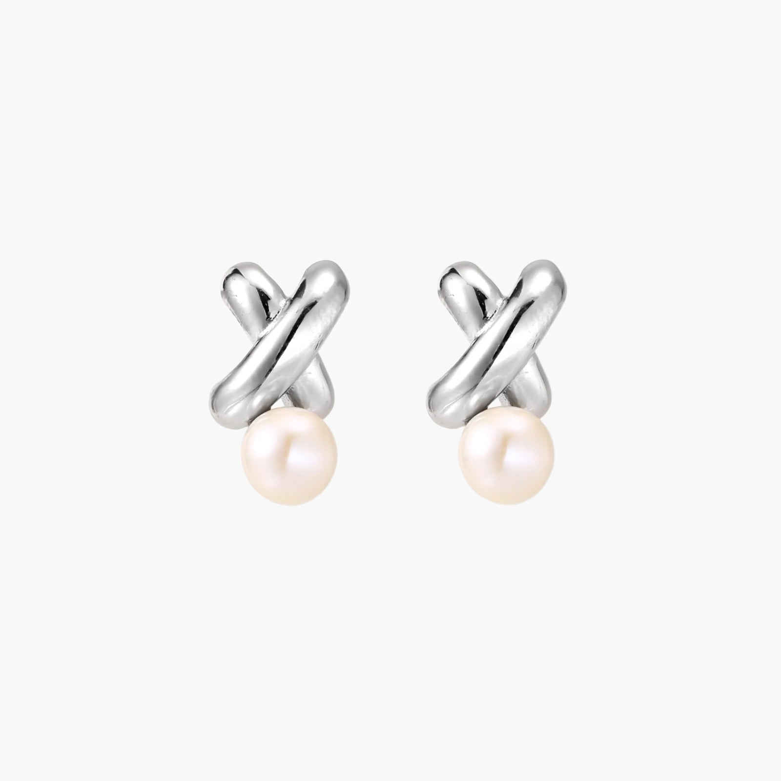 Rhodium-plated silver earrings with twisted X design and freshwater pearl drops on beige background
