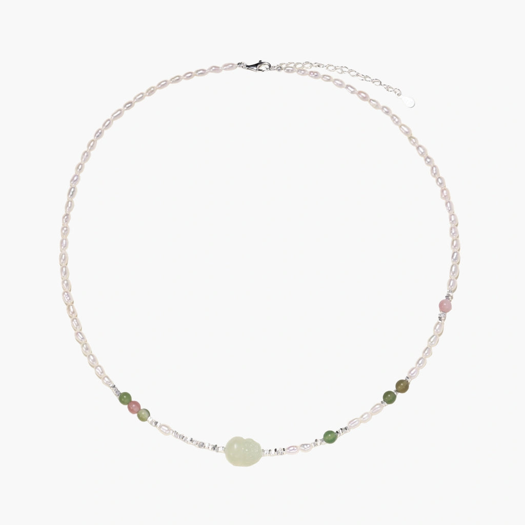 Delicate pearl necklace with pale green serpentine jade centerpiece and colorful agate beads on cream background