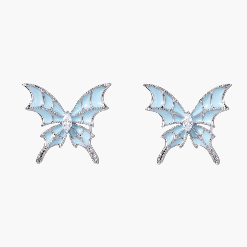 Long silver-tone earrings with powder blue enamel butterfly studs and flowing chain tassels on cream background