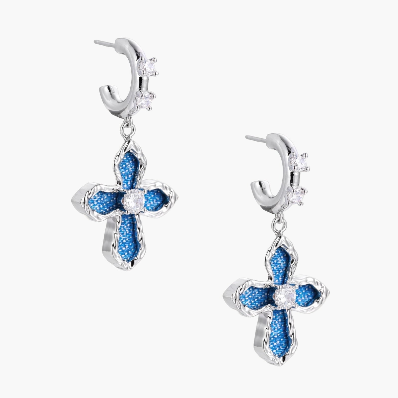 Silver hoops with denim-inlaid cross charms and clear crystals on beige background