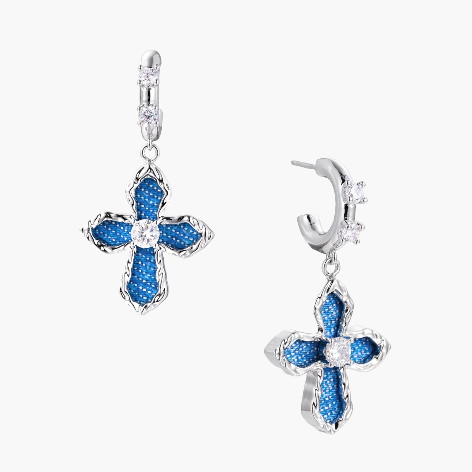 Silver hoops with denim-inlaid cross charms and clear crystals on beige background
