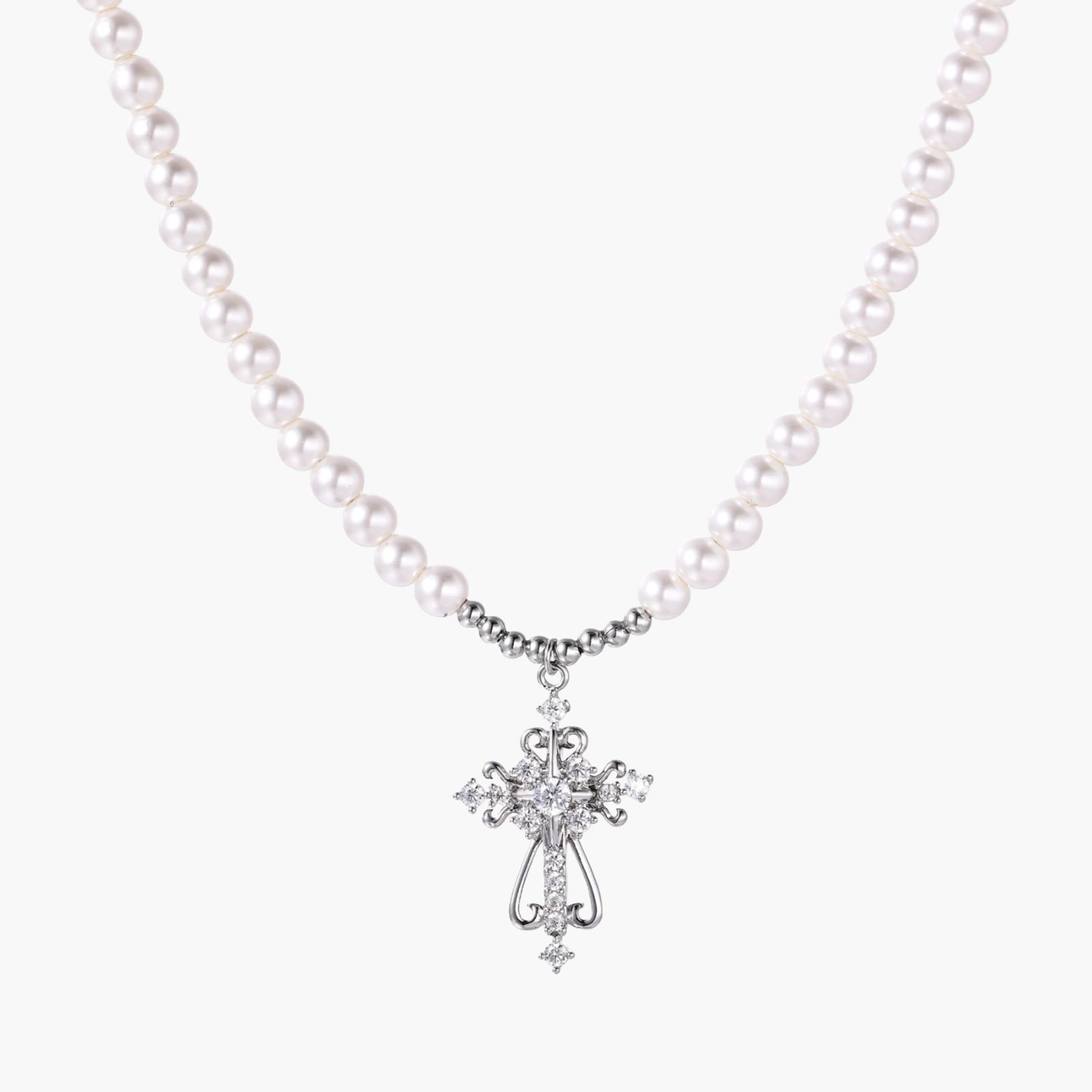 White pearl necklace with ornate silver cross pendant featuring zirconia crystals on cream background.