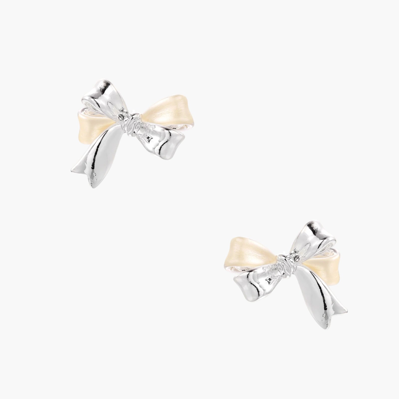 Dimensional bow stud earrings in white gold plated brass with silver and cream two-tone finish on neutral background