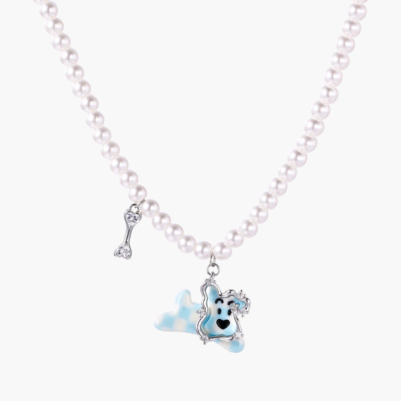 Pearl necklace with playful blue dog pendant accented with sparkly crystals on cream background.