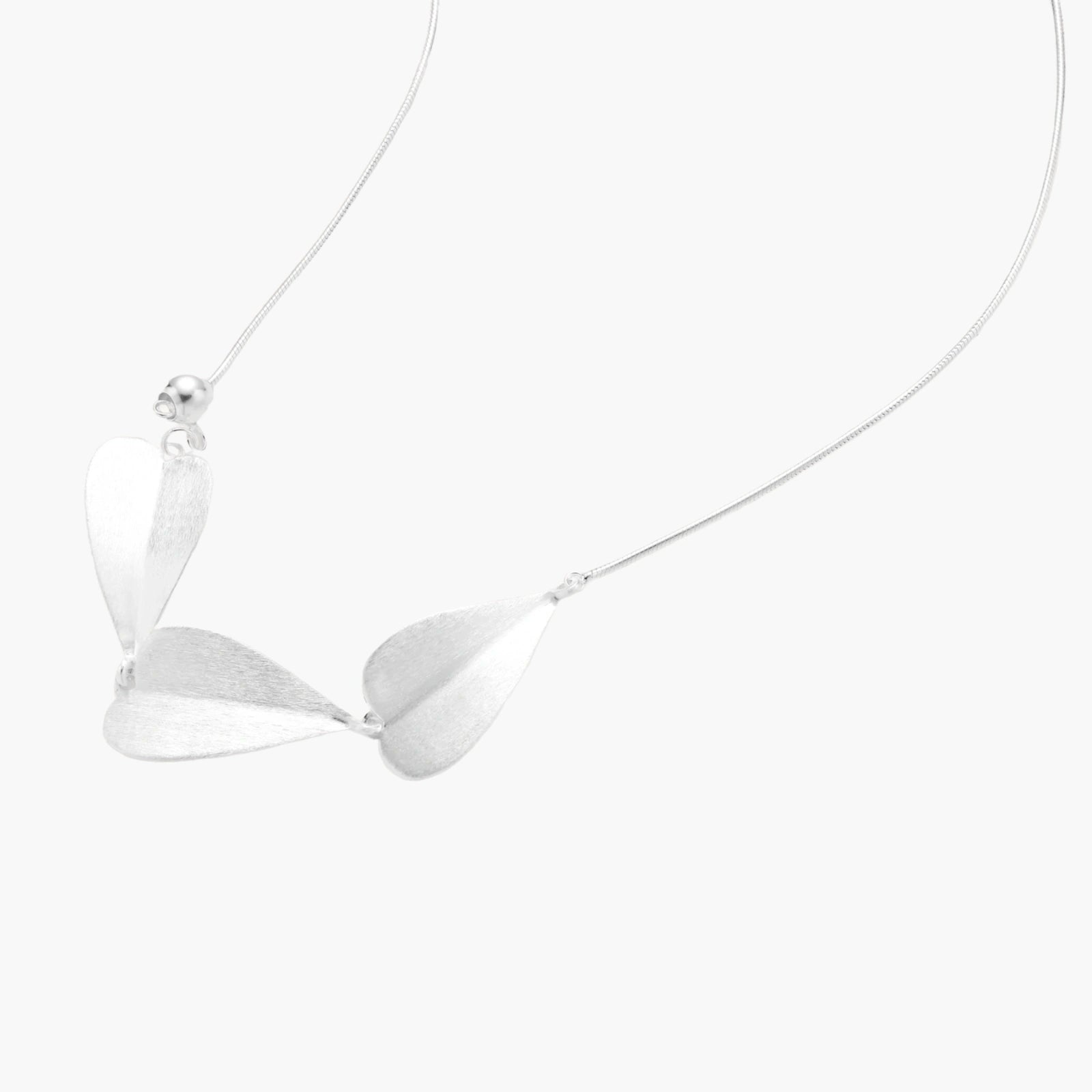 Minimalist sterling silver necklace with three brushed leaf-shaped pendants on delicate chain against white background