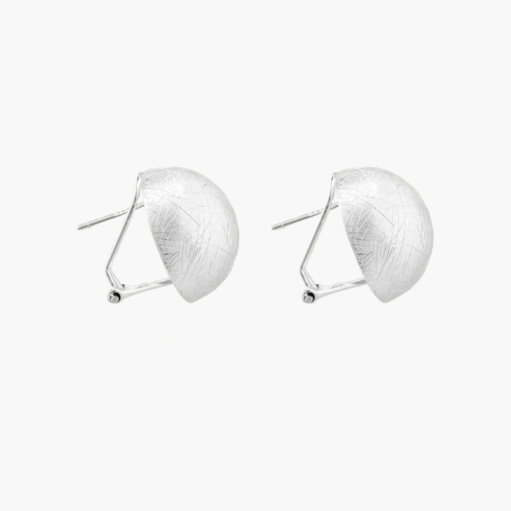 Brushed sterling silver half-dome clip-on earrings with textured surface against cream background