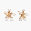 White enamel tropical flower earrings with sculptural gold-plated center and organic petal design on cream background
