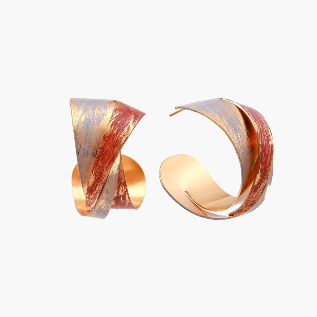 Sculptural gold-plated hoop earrings with diagonal purple and coral enamel stripes in twisted ribbon design