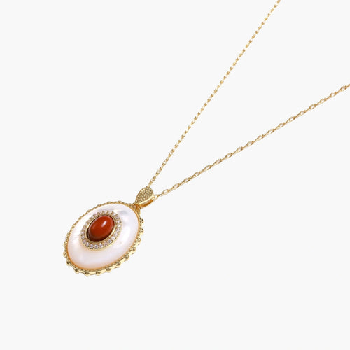 Gold pendant with oval mother-of-pearl frame, amber stone center, and crystal halo on delicate chain