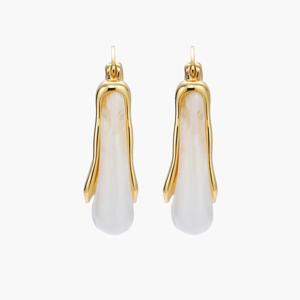 Sculptural gold-plated hoop earrings with flowing curved design and lever-back closure on cream background.