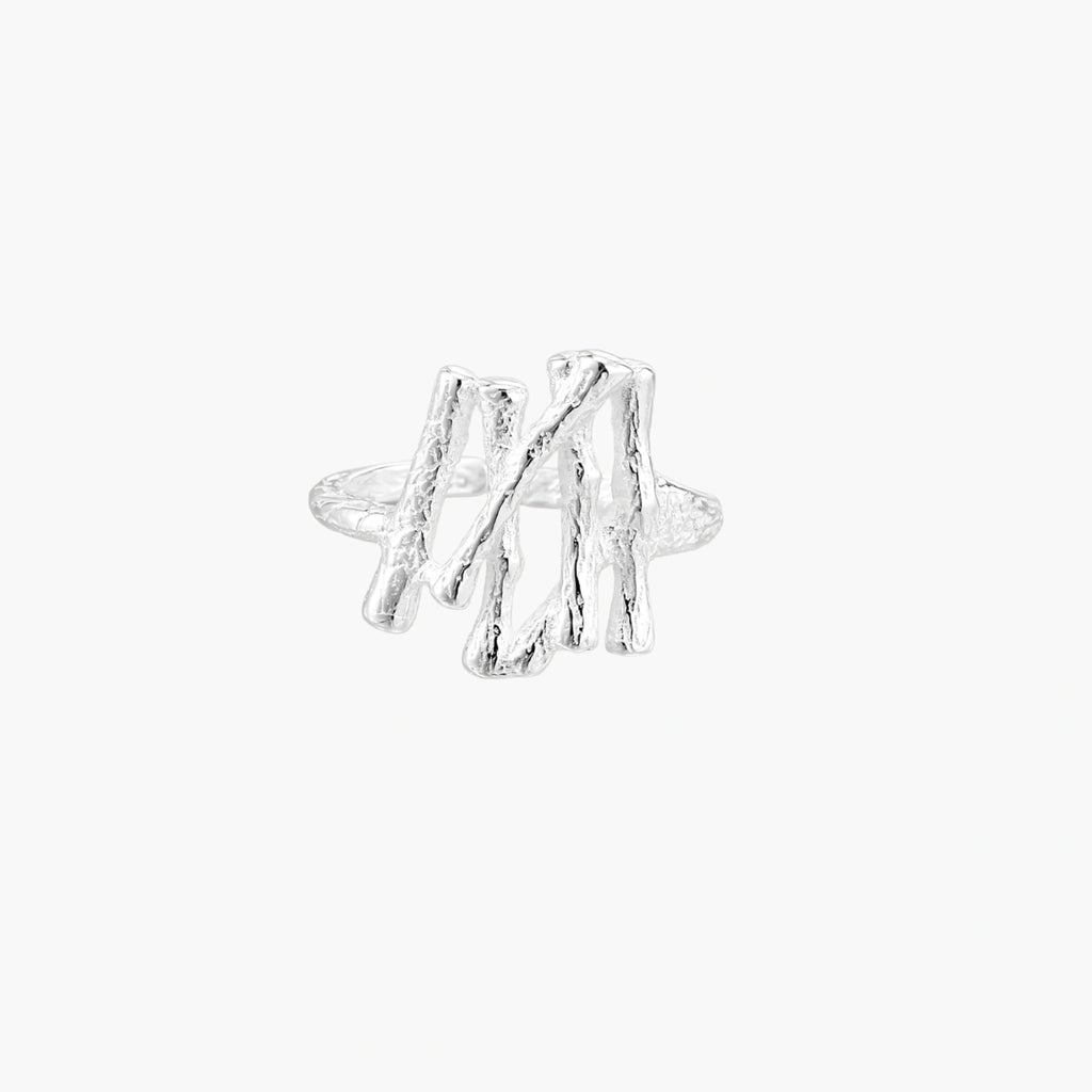 Sculptural sterling silver ring with organic branch design and textured surfaces on cream background