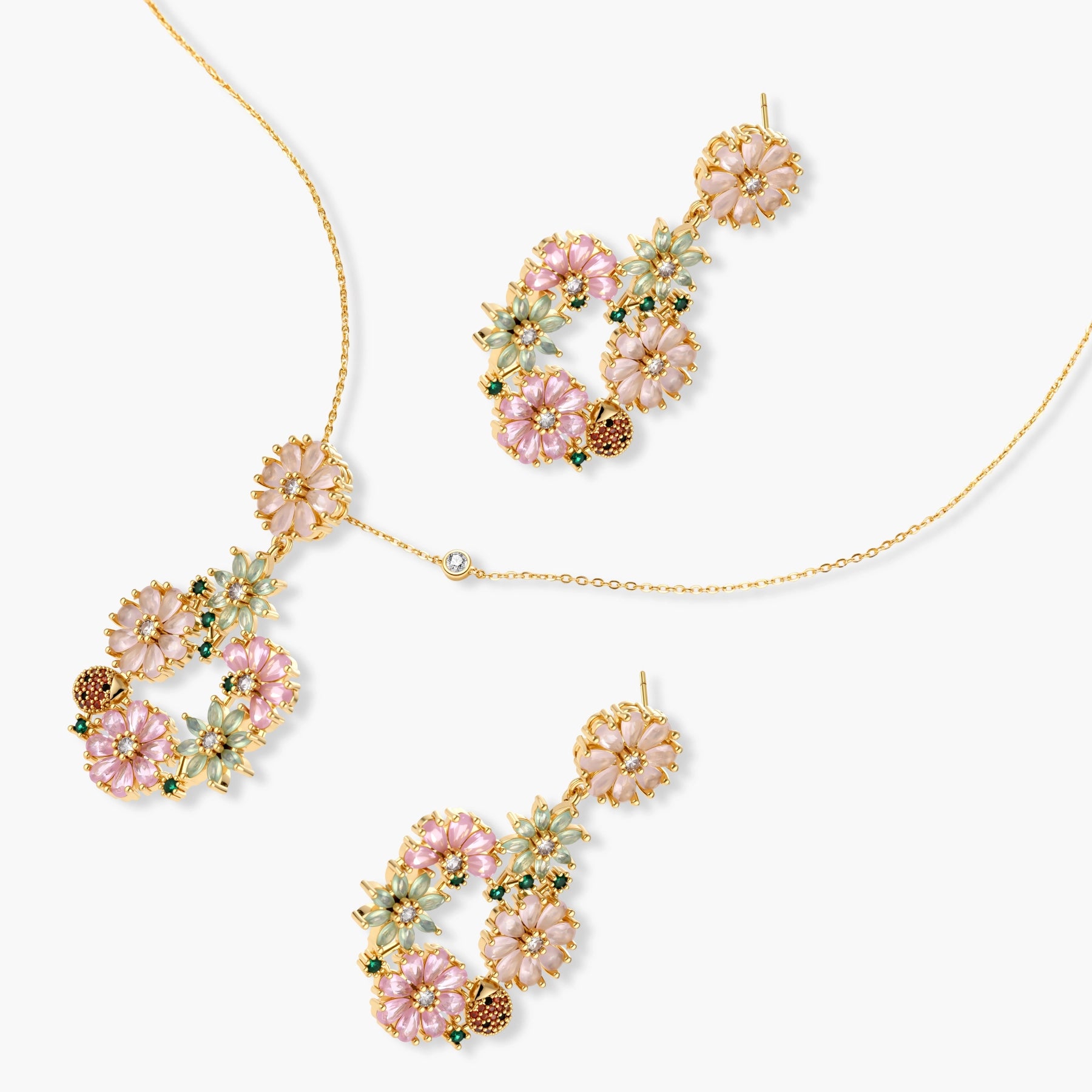 14K gold plated jewelry set with pink and green cubic zirconia flowers arranged in wreath design on cream background